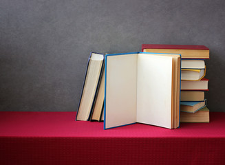 A stack of books on the table with a red tablecloth.