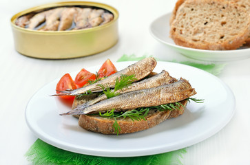 Sandwich with sprats on white plate