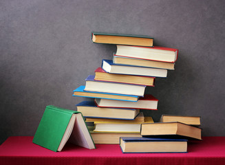 A stack of books on the table with a red tablecloth.
