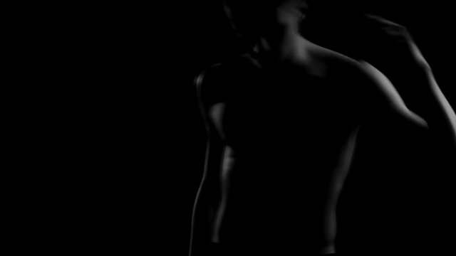 attractive guy with a naked torso beautiful moves his body in the dark