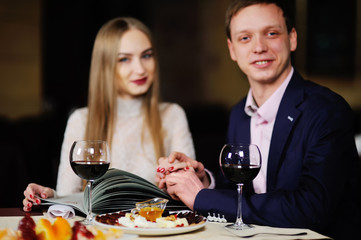 guy with a girl in a restaurant choose dishes from the menu