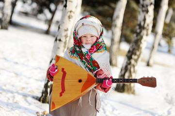 baby girl in a headscarf in the Russian style, with a balalaika