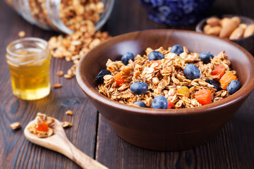 Healthy breakfast. Fresh granola, muesli with berries, honey and milk in a wooden bowl Top view