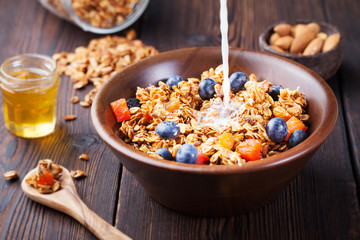 Healthy breakfast. Fresh granola, muesli with berries, honey and milk in a wooden bowl Wooden background