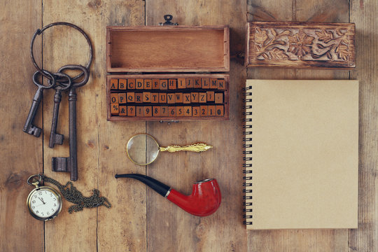 detective concept. Private Detective tools: magnifier glass, old keys, smoking pipe, notebook. top view. vintage filtered image
