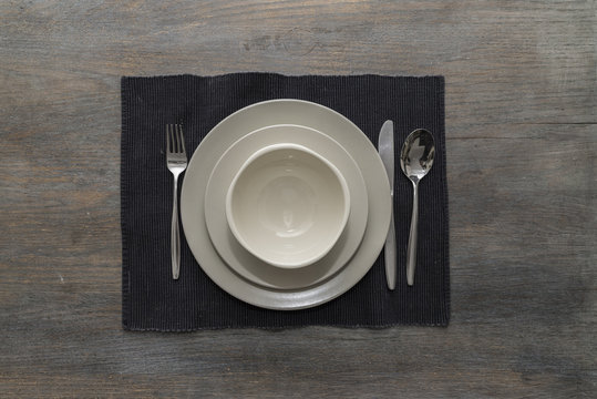 Two off-white plates and a bowl with fork, knife and spoon on a