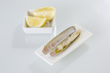 White dish of grilled razor clams with lemon