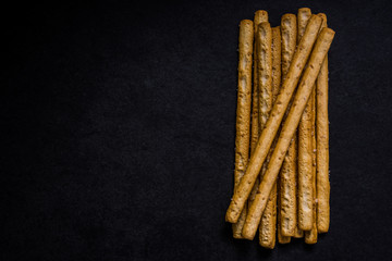 Bread sticks with salt and herbs on dark board