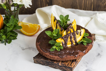 Chocolate cake with chocolate frosting and orange slices,mint. Flowers