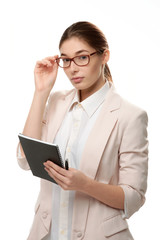 Young stylish woman standing holding a notepad and a pen.
