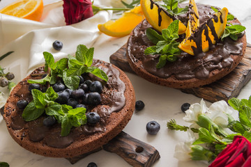 Chocolate cakes with chocolate frosting and orange, and blueberries,mint.