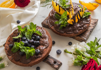 Chocolate cakes with chocolate frosting and orange, and blueberries,mint.