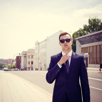 Stylish businessman in the sunglasses near building