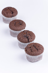 Brown chocolate muffins arranged over white background