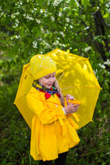 Девочка с желтым зонтом гуляет в парке
