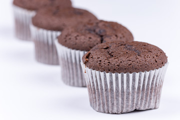 Brown chocolate muffins arranged over white background