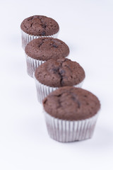 Brown chocolate muffins arranged over white background