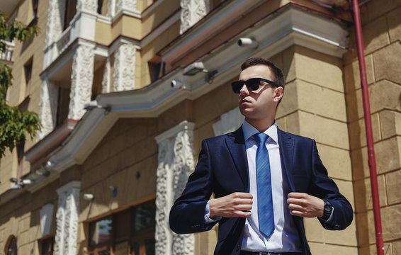 Stylish businessman in the sunglasses near building
