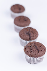 Brown chocolate muffins arranged over white background