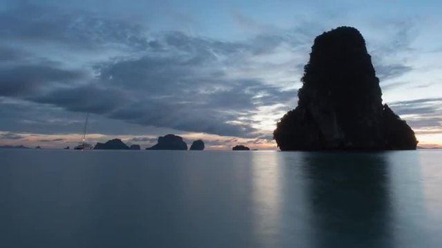 Sunset timelapse of moving clouds on Railey beach Krabi Thailand with limestone mountain reflecting in water