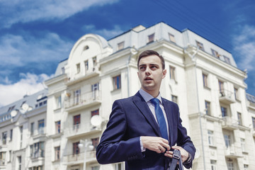 Stylish businessman with the briefcase near building