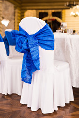 Beautiful fabric bow on the chair. Wedding restaurant for marriage. White decor for bride and groom. Colorful decoration for celebration. Beauty bridal interior