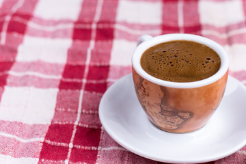 Cup of coffee over red and white tablecloth