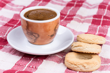 Cup of coffee with round tea cookies on the tablecloth
