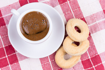 Cup of coffee with round tea cookies on the tablecloth