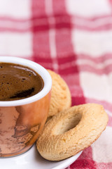 Black coffee with round tea cookies on the plate