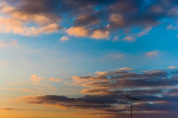 Lonely antenna under sunset sky.