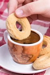 Hand dipping round cookie in to coffee cup