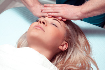 Fototapeta na wymiar Masseur doing massage the head of caucasian woman in the spa sal