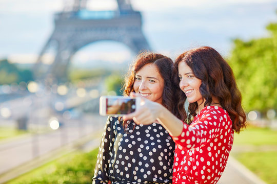 Beautiful twin sisters taking selfie in front of Eiffel Tower