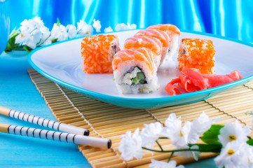 Sakura sushi on a plate with a blue background. Red fish with rice and tobiko