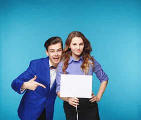 Smiling hipster couple in the jeans and jacket with the sheet in the studio