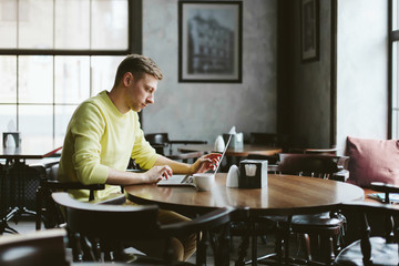 Young man performs work on a laptop
