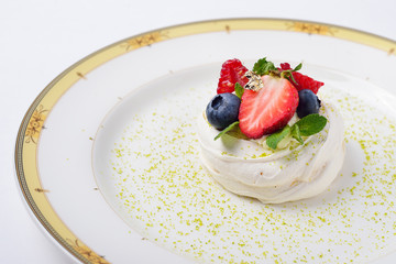pavlova cake decorated with gold, raspberries, blueberries and m