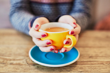 Woman hands with red manicure and cup of coffee