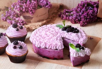 Obraz na płótnie Canvas Homemade blackerry purple souffle cake. Spring traditional delicious sweet pie decorated with blackberry and whipped cream. Lilac flowers on background.