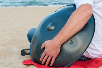 Relax music background. Hands percussion. Musician sit on sand and play the Hang or handpan. The hang is a traditional ethnic drum musical instrument 