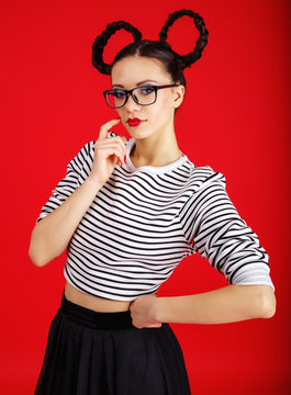 High fashion girl in the glasses with unusual hairstyle like Minnie Mouse in the studio