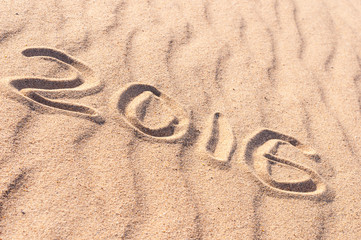 Fototapeta na wymiar Sign 2016 and sun written on sandy beach. Summer travel concept