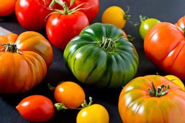 unique colorful ripe tomatoes on black background.