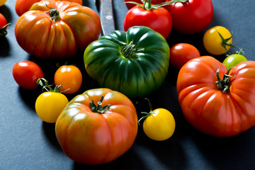 unique colorful ripe tomatoes on black background.