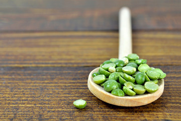 Green lentils in wooden spoon on wooden background