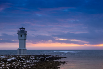 Naklejka premium Beacon on an ocean coast during a sunset. Iceland