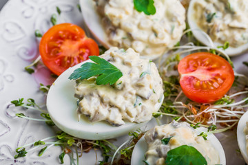 Deviled eggs with mushrooms, mayonnaise and cherry tomatoes on cress sprouts
