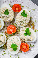 Deviled eggs with mushrooms, mayonnaise and cherry tomatoes on cress sprouts