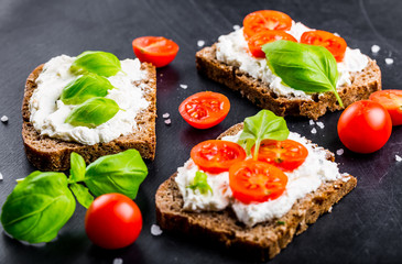 Sandwiches with soft cream cheese, cherry tomatoes and fresh basi